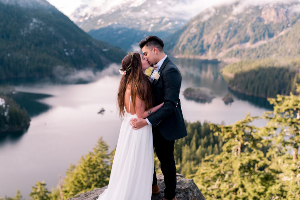 couple kiss at elopement with mountains and lake in background