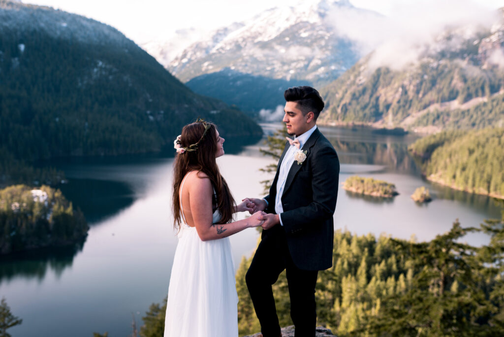 couple hold hands at adventure elopement overlooking lake