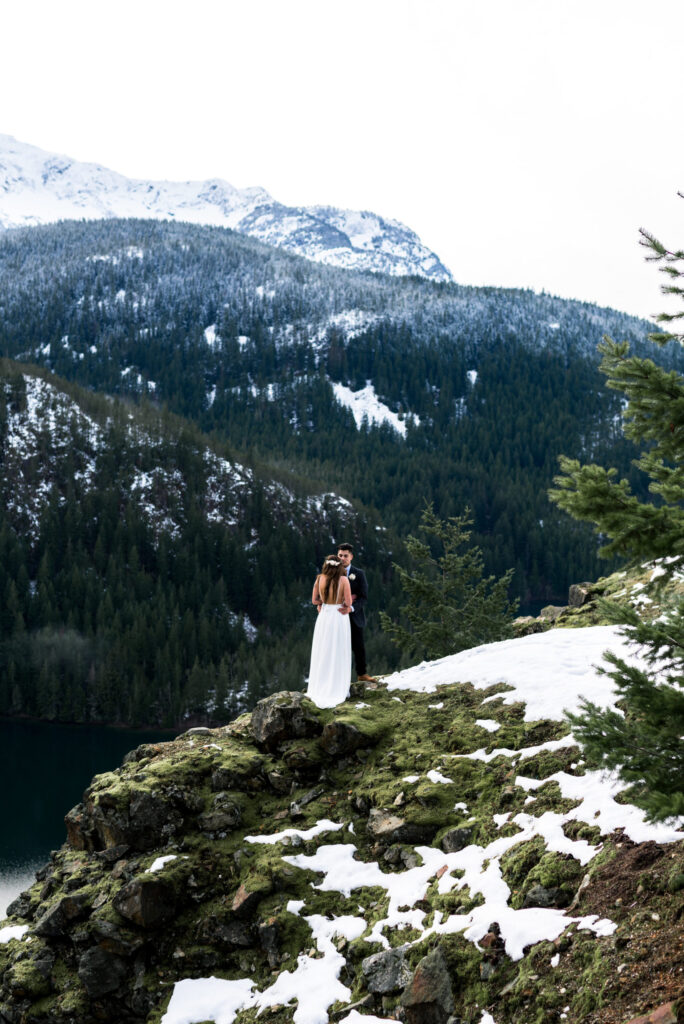 couple standing on snowy cliffside for wedding elopement