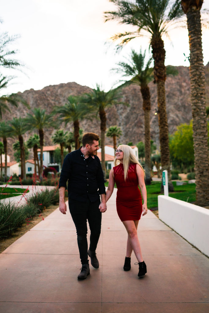 Couple walking down path holding hands in Palm Springs with Palm Trees in the background