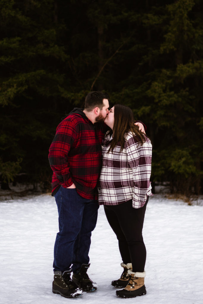 couple kissing during Canmore engagement session in the snow