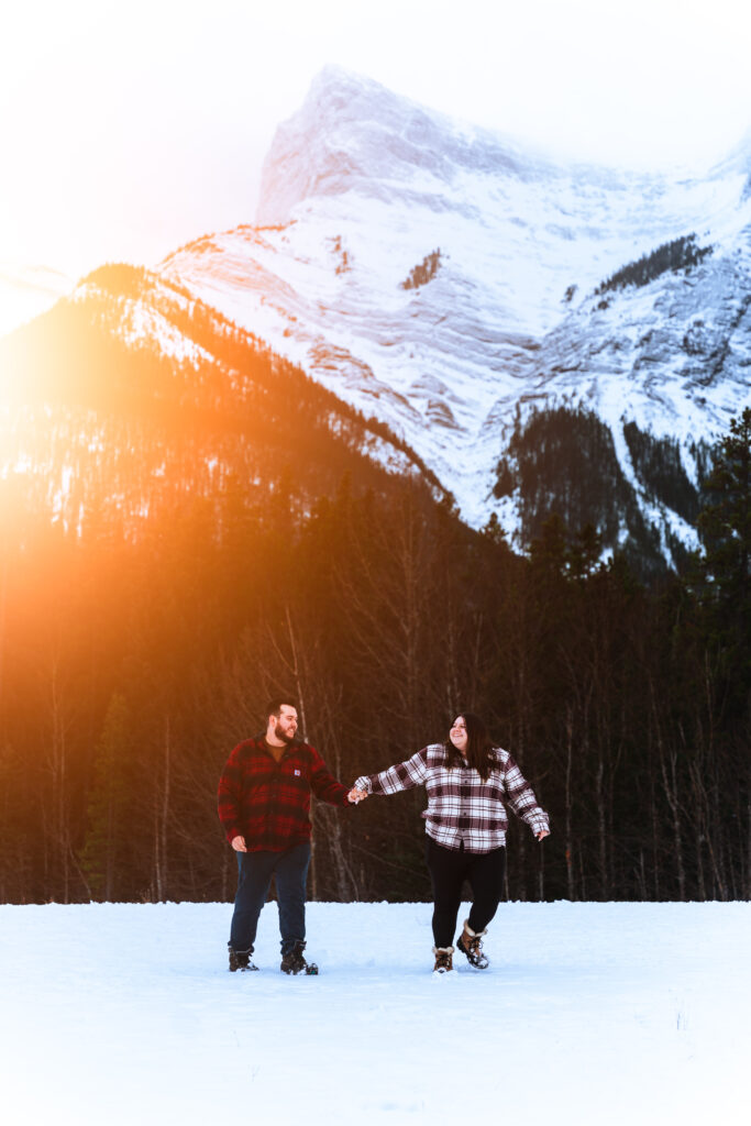 couple holding hands in snow for engagement photos