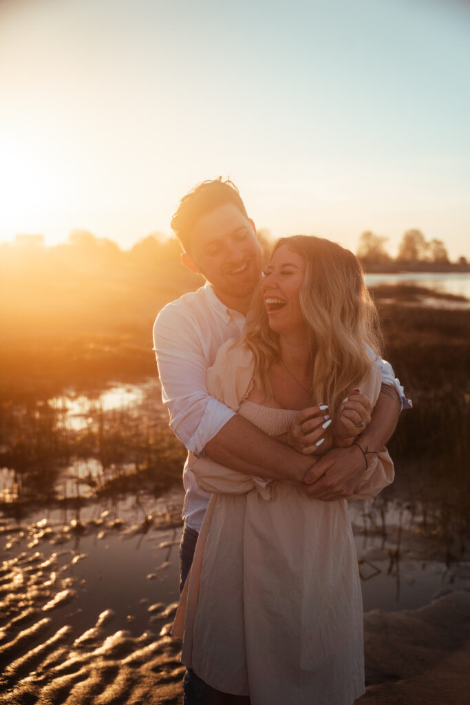 couple laughing on beach during engagement photography session 